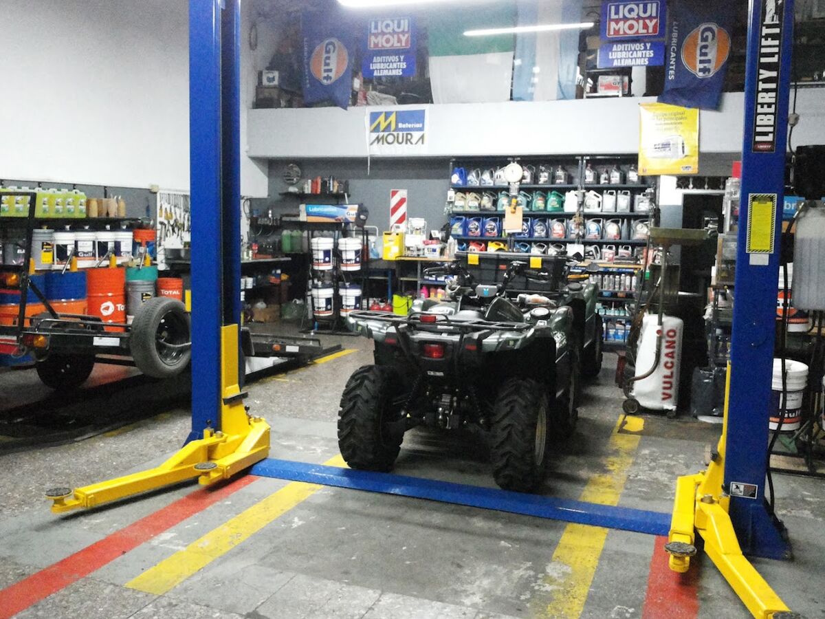 Interior del taller de RPM Lubriruedas con elevadores, un cuatriciclo en reparación y la estantería de aceites Liqui Moly y Gulf